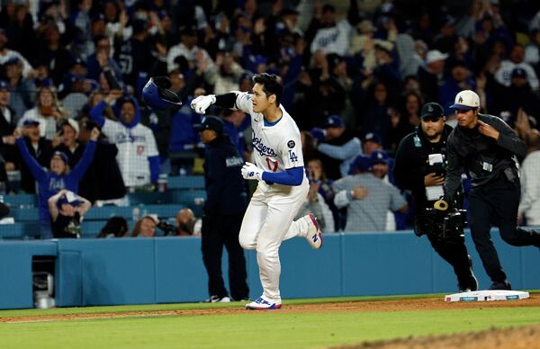 Los Angeles Dodgers' Shohei Ohtani throws his helmet in the air to celebrate a walk-off solo home run against the Atlanta Braves during the ninth inning of a baseball game Wednesday, April 2, 2025, in Los Angeles. (AP Photo/Kevork Djansezian)