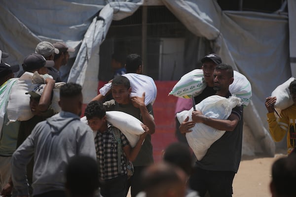 Palestinians carry bags containing food and humanitarian aid packages delivered by the Gaza Humanitarian Foundation, a U.S.-backed organization, in Rafah, southern Gaza Strip, Sunday, June 8, 2025. (AP Photo/Abdel Kareem Hana)