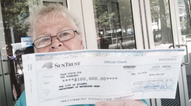 Shelter director Anita Beaty displays a certified check for part of the shelter’s outstanding water bill. City officials refused to accept the partial payment Friday. STEVE VISSER / SVISSER@AJC.COM