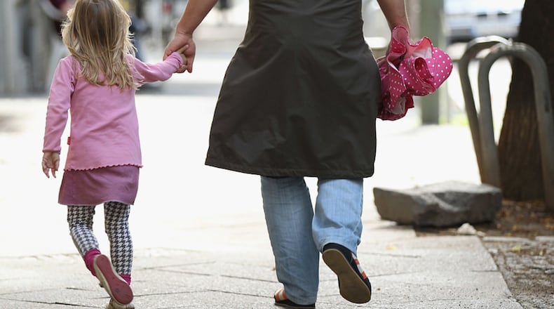 A father and daughter walking hand in hand.