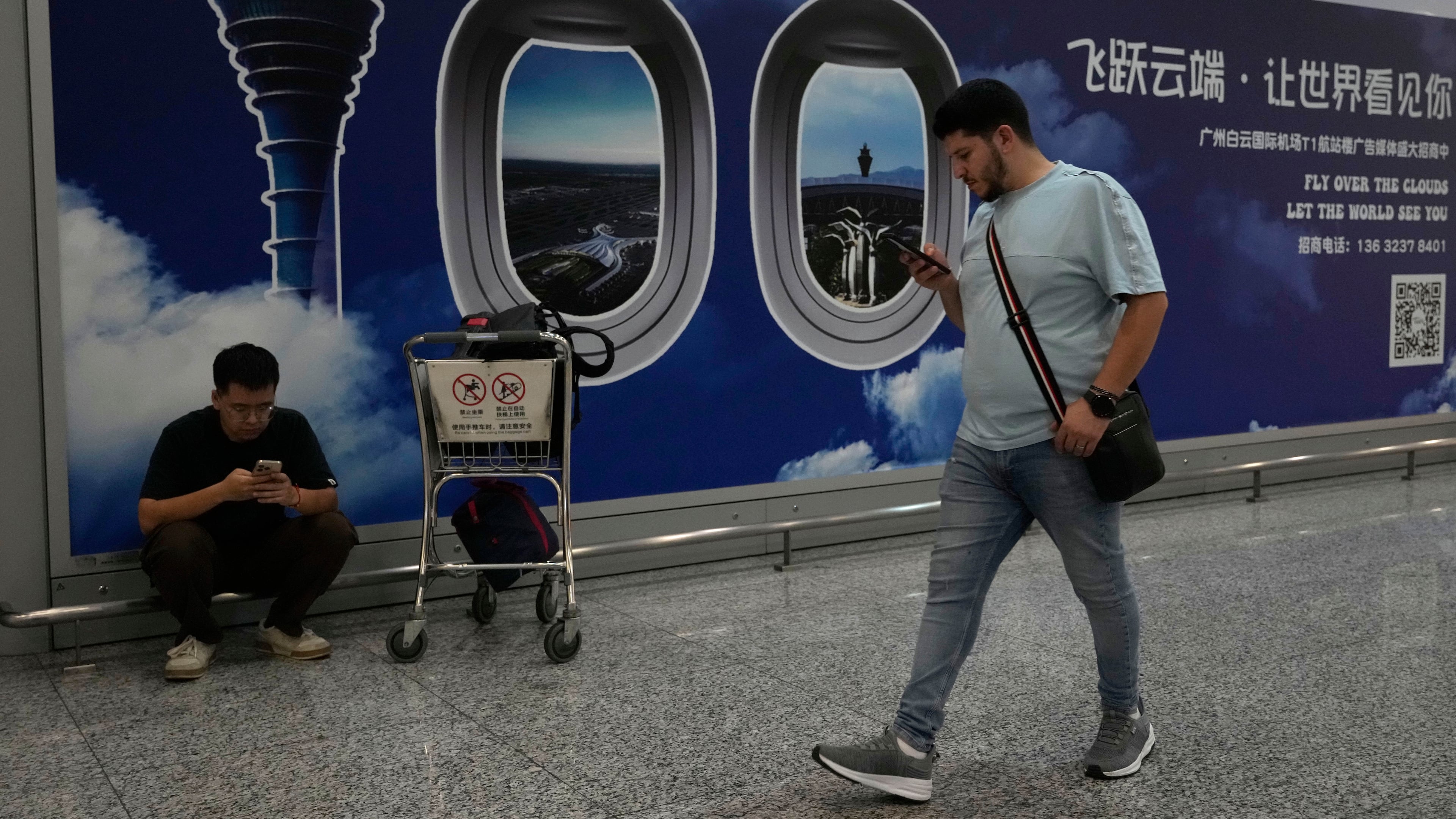 A foreigner walks past a sign board for the Baiyun airport in Guangzhou in southern China's Guangdong province on Nov. 6, 2025. (AP Photo/Ng Han Guan)