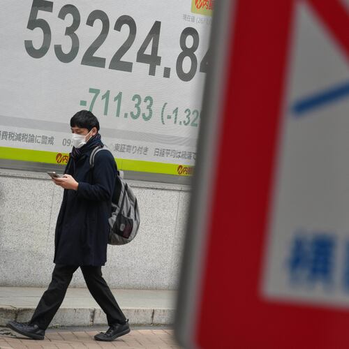 A person walks in front of an electronic stock board showing Japan's Nikkei index at a securities firm Monday, Jan. 19, 2026, in Tokyo. (AP Photo/Eugene Hoshiko)