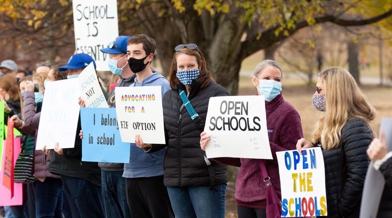 Parents and their children line along 10th Street N.E. near Piedmont Park on  Sunday, December 6, 2020, during a rally calling for the safe, immediate opening of Atlanta and DeKalb County schools. (Steve Schaefer for The Atlanta Journal-Constitution)