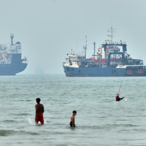 FILE - Children wade in the water with cargo ships at anchor in the background and a fisherman nearby, in the Strait of Hormuz off Bandar Abbas, Iran, Tuesday, June 30, 2026. (Amirhosein Khorgooi/ISNA via AP,File)