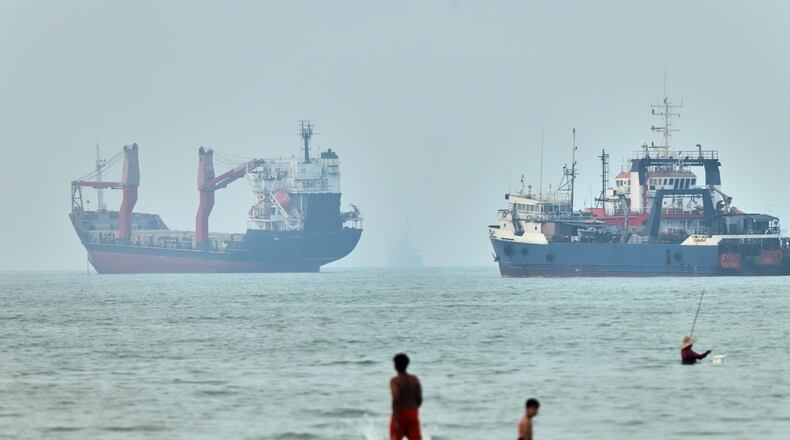 FILE - Children wade in the water with cargo ships at anchor in the background and a fisherman nearby, in the Strait of Hormuz off Bandar Abbas, Iran, Tuesday, June 30, 2026. (Amirhosein Khorgooi/ISNA via AP,File)