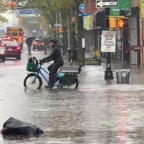 A cyclist rides through floodwaters during a rainstorm in New York, Thursday, Oct. 30, 2025. (AP Photo/David Martin)