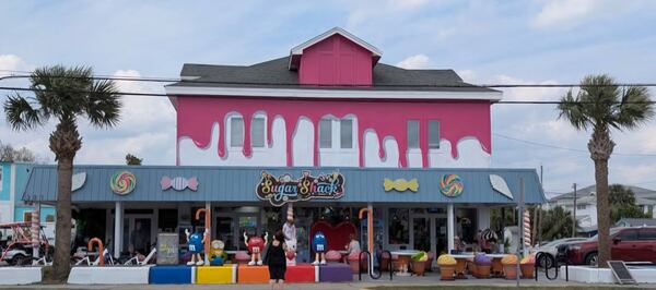 The exterior of an ice cream shop painted in bright colors, with a pink accent at the top that looks like melting ice cream dripping down the facade.