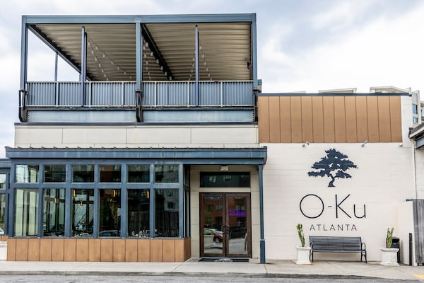 The exterior of O-Ku's Atlanta location. It shows a first floor restaurant with an open-air seating area on the second floor.