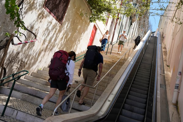 People climb stairs in Lisbon old centre after the escalator stopped working following a power outage, Monday, April 28, 2025. (AP Photo/Armando Franca)