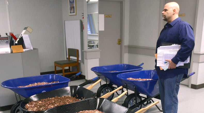 Nick Stafford waits for his number to be called Wednesday, Jan. 11, 2017, as he stands beside of 5 wheelbarrows full of change, mostly pennies, at the DMV in Lebanon, Va. Stafford was paying the sales tax on two cars that he was titling. Stafford had paid $165 to file three lawsuits in Russell County General District Court: two against specific employees at the Lebanon DMV and one against the DMV itself., which means he spent $1,005 to get 10 phone numbers and the satisfaction of delivering 300,000 pennies. Not to mention the nearly $3,000 he paid the DMV for the cars. (David Criggeru/The Bristol Herald-Courier via AP)