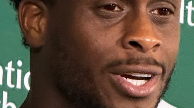 New York Jets quarterback Geno Smith, wearing red contact lenses, speaks to reporters after practice at the team’s training facility in Florham Park, N.J., on Thursday, Aug. 6, 2026. (AP Photo/Dennis Waszak Jr.)