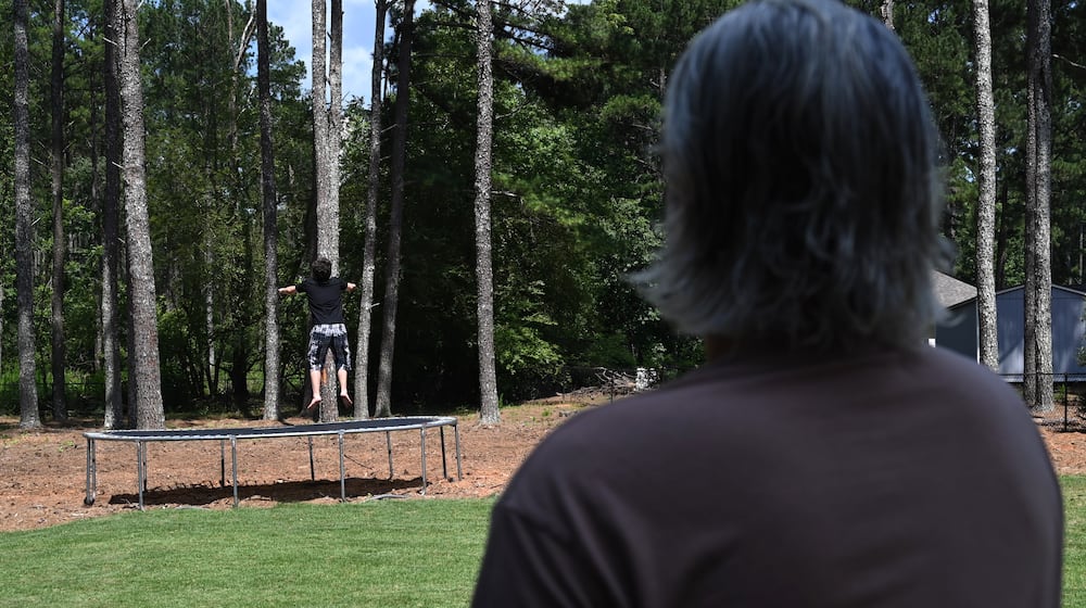 Gabe Richard watches his son play in their backyard. Richard and his wife, Nichole, say their son, who has autism, was harmed by a state program designed to help students with emotional and behavioral disabilities. (Hyosub Shin/AJC)