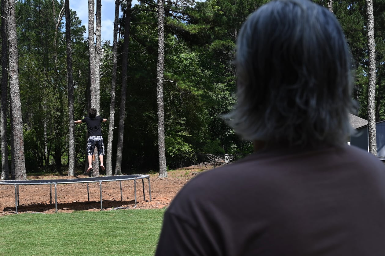 Gabe Richard watches his son play in their backyard. Richard and his wife, Nichole, say their son, who has autism, was harmed by a state program designed to help students with emotional and behavioral disabilities. (Hyosub Shin/AJC)