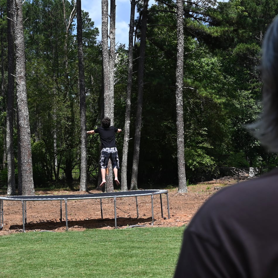 Gabe Richard watches his son play in their backyard. Richard and his wife, Nichole, say their son, who has autism, was harmed by a state program designed to help students with emotional and behavioral disabilities. (Hyosub Shin/AJC)