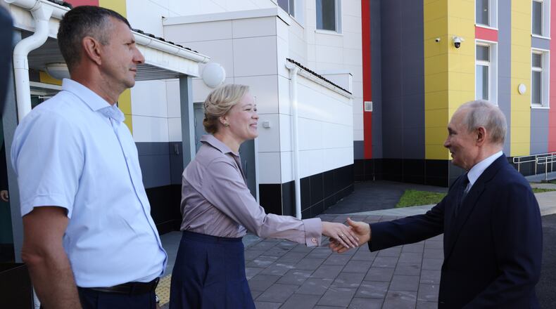 Russian President Vladimir Putin, right, visits the Secondary School named after the Hero of Russia Eduard Norpolov in Kurilsk on the Iturup Island, the largest of the Kuril Islands of Russia's fareast, on Thursday, Aug. 13, 2026. (Gavriil Grigorov, Sputnik, Kremlin Pool Photo via AP)