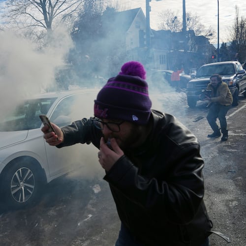 Protesters try to avoid tear gas dispersed by federal agents, Monday, Jan. 12, 2026 in Minneapolis (AP Photo/Adam Gray)