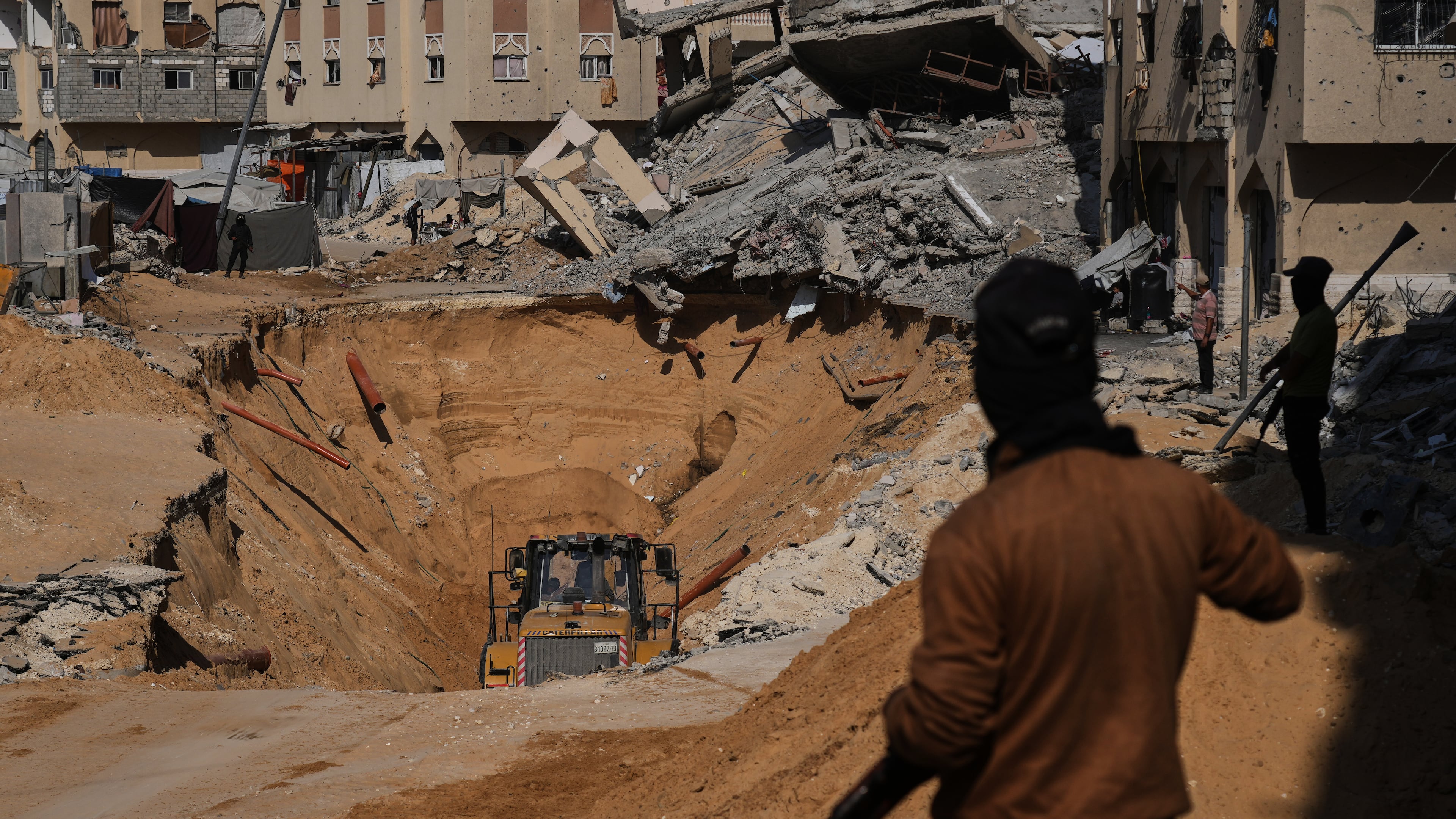 Members of the Hamas militant group search underground for the bodies of Israeli hostages amid destroyed buildings in Khan Younis, in the southern Gaza Strip, Sunday, Oct. 19, 2025. (AP Photo/Abdel Kareem Hana)