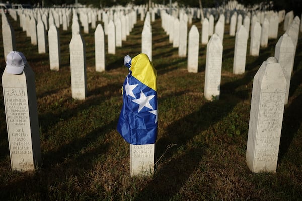 A Bosnian flag is seen at a grave stone at the Memorial Center for those killed in Srebrenica genocide in Potocari, Bosnia, Friday, July 11, 2025. (AP Photo/Armin Durgut)