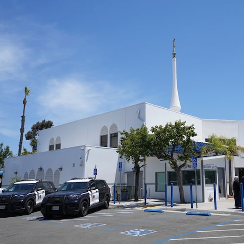 FILE - People gather as police vehicles are parked outside of the Islamic Center of San Diego, the day after a shooting, May 19, 2026, in San Diego. (AP Photo/Jae C. Hong, File)