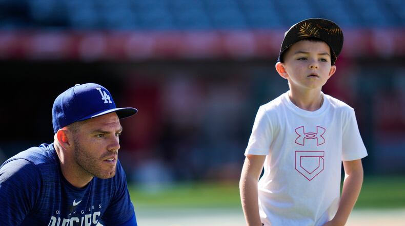 FILE - Los Angeles Dodgers first baseman Freddie Freeman (5) and his son, Charlie Freeman, participate in batting practice before a baseball game against the Los Angeles Angels in Anaheim, Calif., June 21, 2023. (AP Photo/Ashley Landis, File)