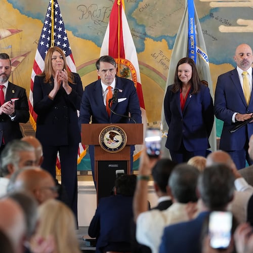 Audience members give a standing ovation as Acting Attorney General Todd Blanche, center, speaks at an event where federal prosecutors announced charges against former Cuban President Raul Castro in the 1996 downing of civilian planes operated by Miami-based exiles, Wednesday, May 20, 2026, in Miami. Also shown, from left, are, Florida Attorney General James Uthmeier; Jason A. Reding Quiñones, U.S. attorney for the southern district of Florida; Miami Dade College President Madeline Pumariega; Sen. Ashley Moody, R-Fla.; and FBI Deputy Director Christopher Raia. (AP Photo/Rebecca Blackwell)