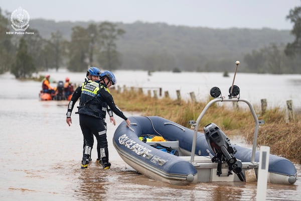 In this photo provided by the New South Wales Police, emergency workers wade through floodwaters as they prepare inflatable boats to effect rescues near Taree, Australia, Thursday, May 22, 2025. (NSW Police via AP)