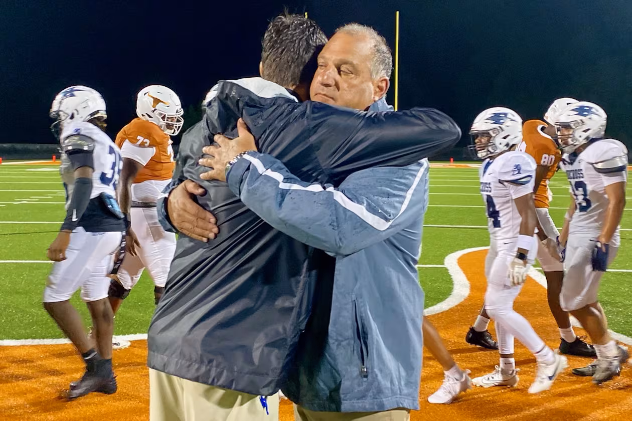 Norcross High coach Keith Maloof hugs his son Tyler Maloof, the coach at Lanier High, after the Blue Devils’ 31-10 win on Friday, Aug. 16, 2024. It was the first father-son coaching matchup in GHSA football since 2006. (Ken Sugiura/AJC 2024)