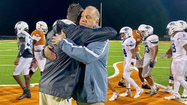 Norcross High coach Keith Maloof hugs his son Tyler Maloof, the coach at Lanier High, after the Blue Devils' 31-10 win at Lanier Aug. 16, 2024. It was the first father-son coaching matchup in GHSA football since 2006. (Ken Sugiura/AJC)
