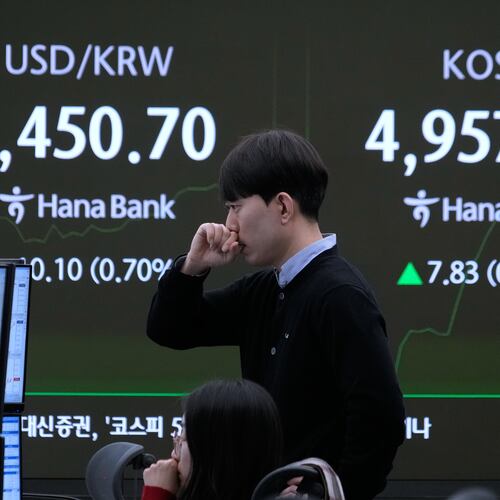Currency traders watch monitors near a screen showing the Korea Composite Stock Price Index (KOSPI) and the foreign exchange rate between U.S. dollar and South Korean won, left, at the foreign exchange dealing room of the Hana Bank headquarters in Seoul, South Korea, Tuesday, Jan. 27, 2026. (AP Photo/Ahn Young-joon)