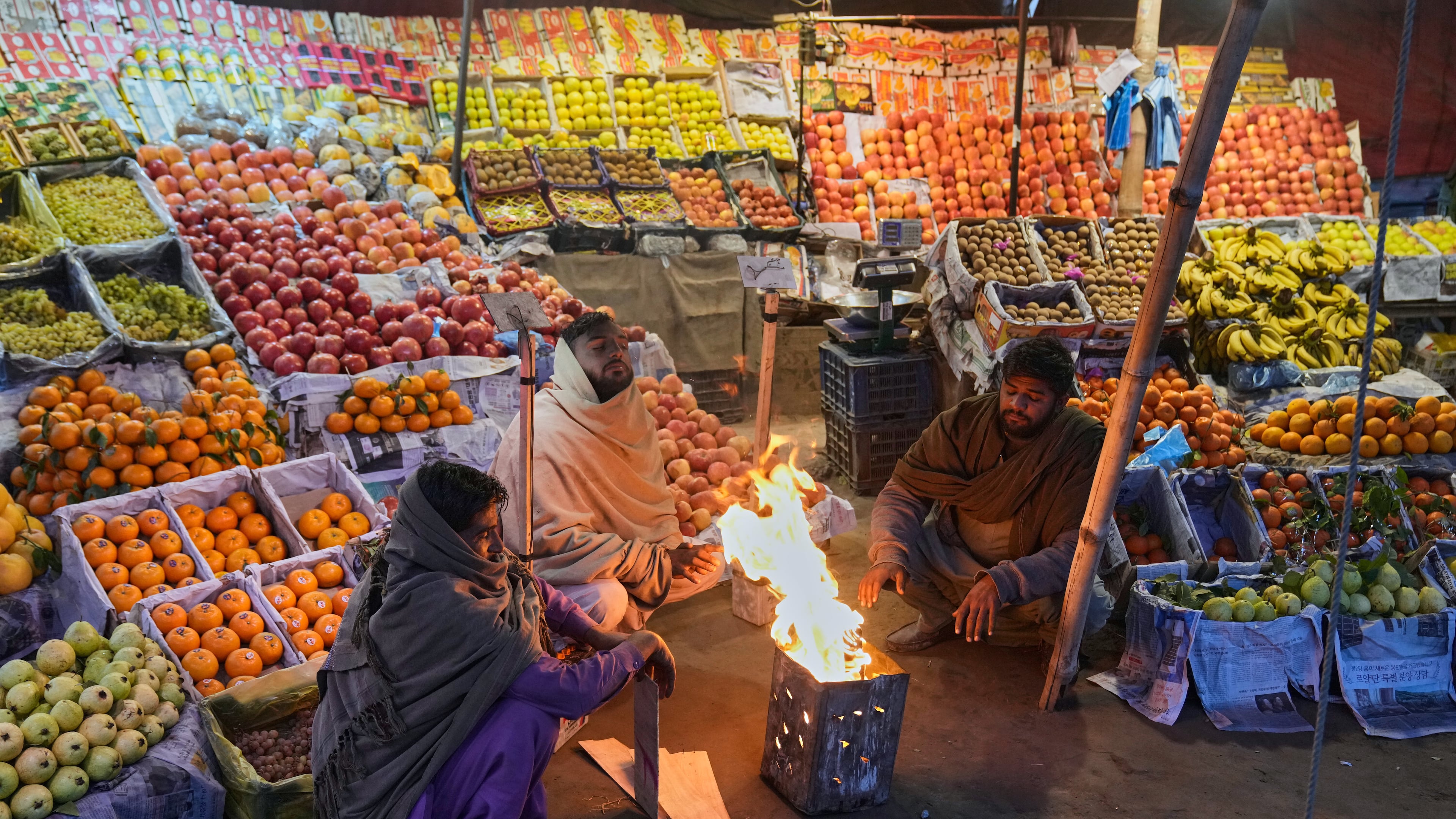 Vendors warm themselves around a fire on a cold morning in Lahore, Pakistan, Tuesday, Dec. 9, 2025. (AP Photo/K.M. Chaudary)