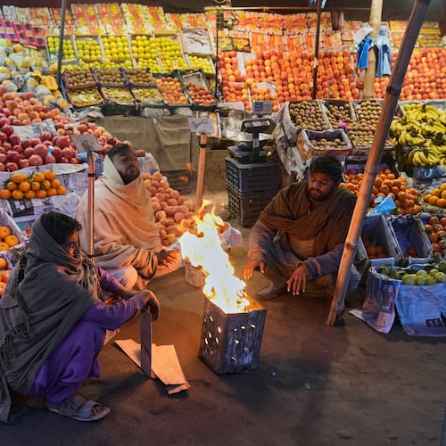 Vendors warm themselves around a fire on a cold morning in Lahore, Pakistan, Tuesday, Dec. 9, 2025. (AP Photo/K.M. Chaudary)