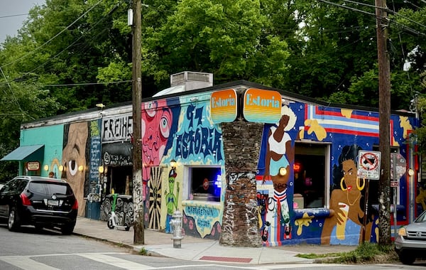 The exterior of a bar with a sign that says Estoria and walls covered in murals and graffiti.