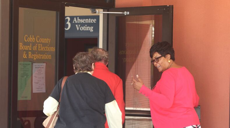 An election worker holds the door open for residents looking to vote early in the 6th Congressional District special election April 10 in Marietta. HENRY TAYLOR / HENRY.TAYLOR@AJC.COM