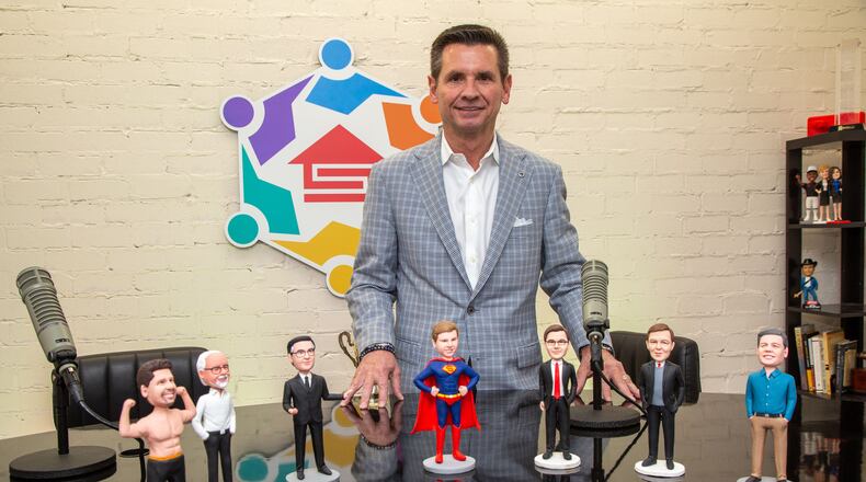 Supreme Lending CEO, Pat Flood, poses behind a group of bobblehead dolls that he has had made of the guests that appear on his monthly podcast at their Alpharetta offices. For the Top Workplaces section (Photo by Phil Skinner)