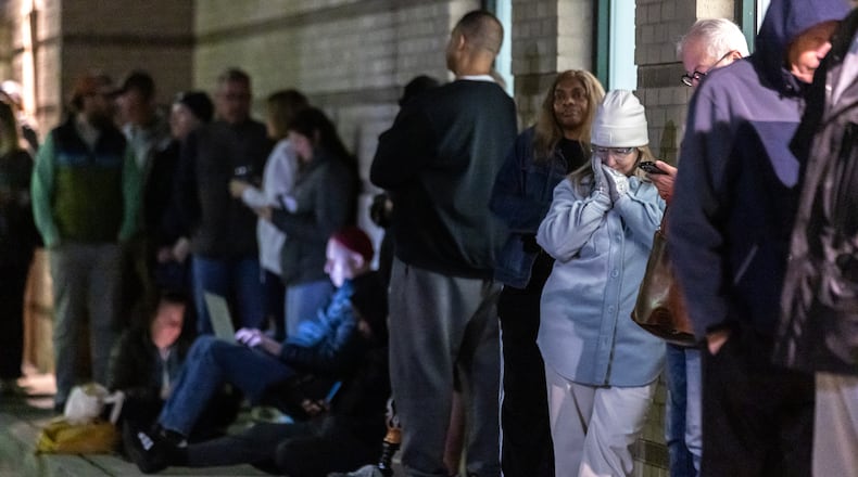 Jennifer Newlin (right) tries to stay warm along with fellow voters before the polls open Oct. 15 at the Joan P. Garner Library at 980 Ponce De Leon Ave North in Atlanta. (John Spink/The Atlanta Journal-Constitution)