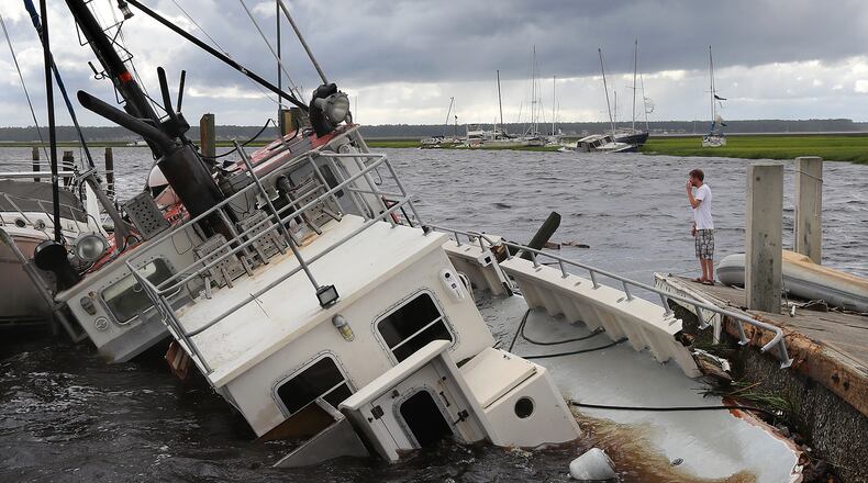 Dozens of boats are blown into the marsh and a shrimp boat sits on the bottom as local resident Michael Whitemore, 36, checks to see whether a friend’s boat survived at Langs Marina after Hurricane Irma hit St. Marys on Monday, Sept. 11, 2017.