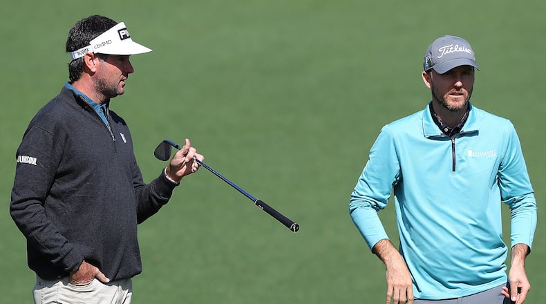 Two-time Masters champion Bubba Watson (left) gives fellow University of Georgia golfer Russell Henley some pointers on pin locations at the second green Monday while they play a practice round for the Masters at Augusta National Golf Club. (Curtis Compton / Curtis.Compton@ajc.com)