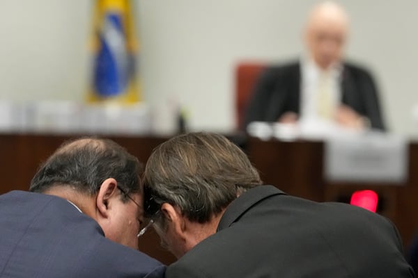 Brazil's former President Jair Bolsonaro, right, talks with his lawyer as he sits before Supreme Court Judge Alexandre de Moraes during his trial, along with others, charged with an alleged coup plot to keep him in office after his 2022 election defeat, in Brasilia, Brazil, Tuesday, June 10, 2025. (AP Photo/Eraldo Peres)