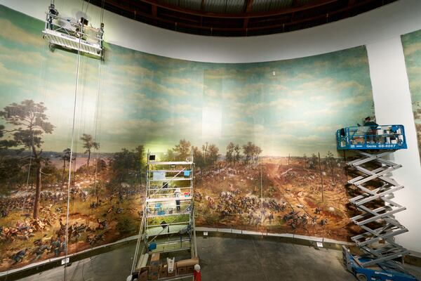 Conservators on scissor lifts complete the restoration of “The Battle of Atlanta,” including adding back one of the vertical sections that was missing, seen at right. Artisans used chopsticks wrapped with cotton bolls to clean the mammoth painting. CONTRIBUTED: ATLANTA HISTORY CENTER