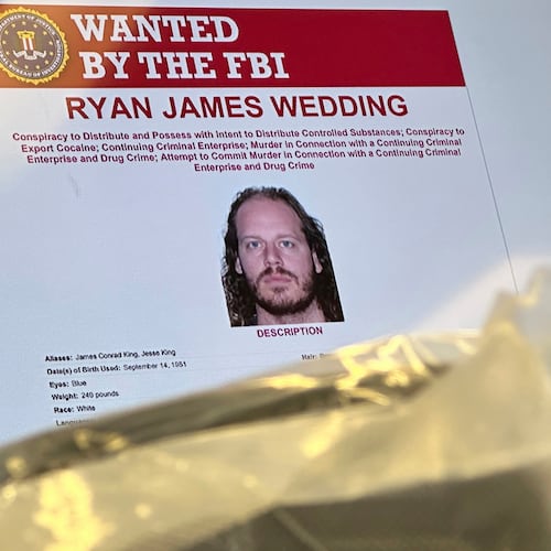 FILE - An image of former Canadian Olympic snowboarder Ryan Wedding, who is a fugitive and been charged with allegedly running and participating in a transnational drug trafficking operation, is displayed on a video monitor along with bricks of cocaine, foreground, during a news conference at the FBI offices in Los Angeles, Oct. 17, 2024. (AP Photo/Damian Dovarganes, File)