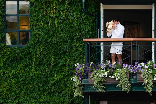 FILE - Carlos Alcaraz of Spain kisses his trophy on the balcony of Centre Court for the crowds gathered below after defeating Novak Djokovic of Serbia in the men's singles final at the Wimbledon tennis championships in London, Sunday, July 14, 2024. (AP Photo/Kirsty Wigglesworth,File)