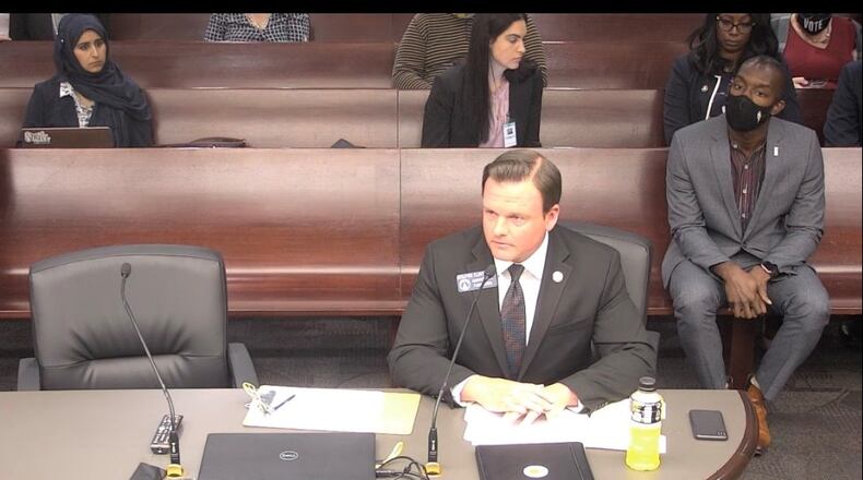 State Sen. Clint Dixon addresses a Senate panel concerning changes he wants in Gwinnett County elections. Gwinnett school board Chairman Everton Blair, seated behind him, opposes the measure.