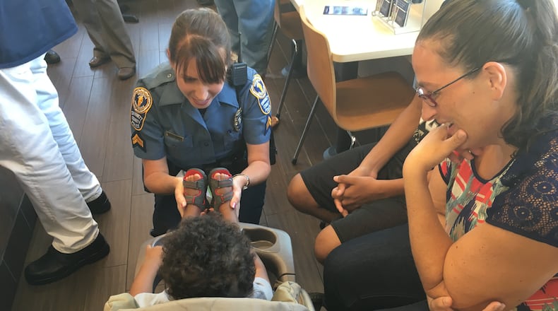 Gwinnett County police Cpl. Michele Pihera plays with a child Tuesday morning at a Dunkin' Donuts in Dacula while the boy's mom, Kylee Fulton, looks on. TYLER ESTEP/ TYLER.ESTEP@COXINC.COM