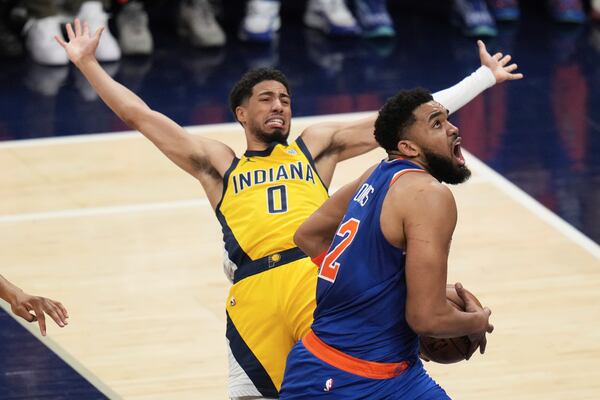 New York Knicks center Karl-Anthony Towns, right, drives to the basket against Indiana Pacers guard Tyrese Haliburton during the first half of Game 3 of the Eastern Conference finals of the NBA basketball playoffs Sunday, May 25, 2025, in Indianapolis. (AP Photo/Jeff Roberson)