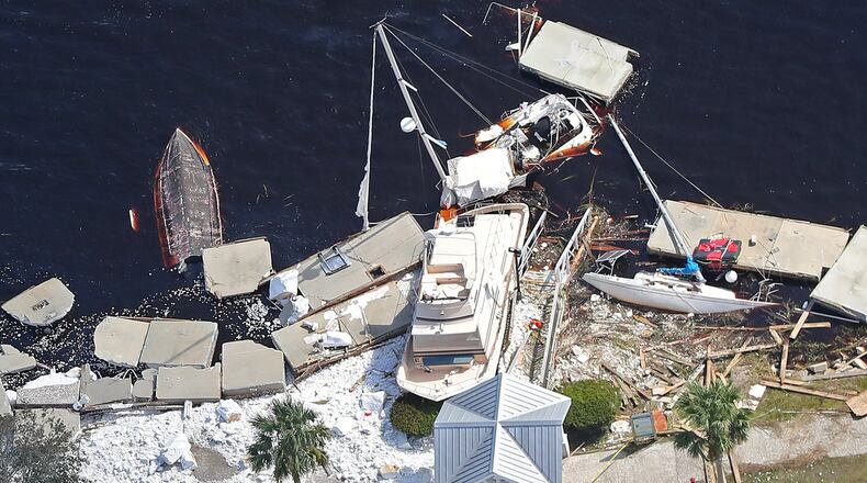 Local residents walk past debris from docks that were shredded and boats that were sunk littering the shoreline after Hurricane Irma on Tuesday, September 12, 2017, at St. Marys on the Georgia coast. Curtis Compton / ccompton@ajc.com