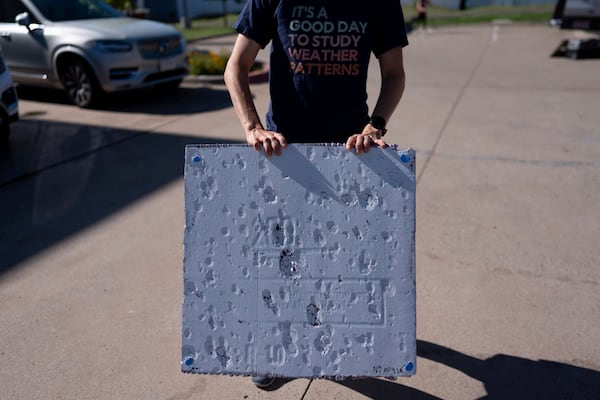 Hannah Vagasky holds a foam board hail pad covered with impact dents in a parking lot Tuesday, June 3, 2025, in Shamrock, Texas, as the team prepares for a day of hailstorm chasing. The hail pad is used to measure the size, angle of impact and intensity of hail. (AP Photo/Carolyn Kaster)