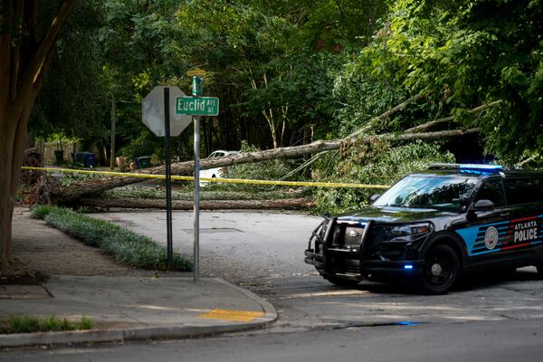 An Atlanta police officer parks in front of a tree that fell across Alta Avenue at Euclid Avenue in Atlanta's Inman Park on Thursday, June 26, 2025. (Ben Hendren for the AJC)