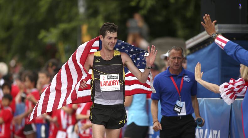 Christo Landry celebrates with fans after winning the men’s field of the 2014 AJC Peachtree Road Race. PHOTO BY / JASON GETZ