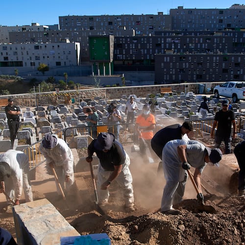 Funeral workers bury migrants who died while trying to cross from Morocco into the Spanish exclave of Ceuta, Friday, Aug. 21, 2026. (AP Photo/Antonio Sempere)