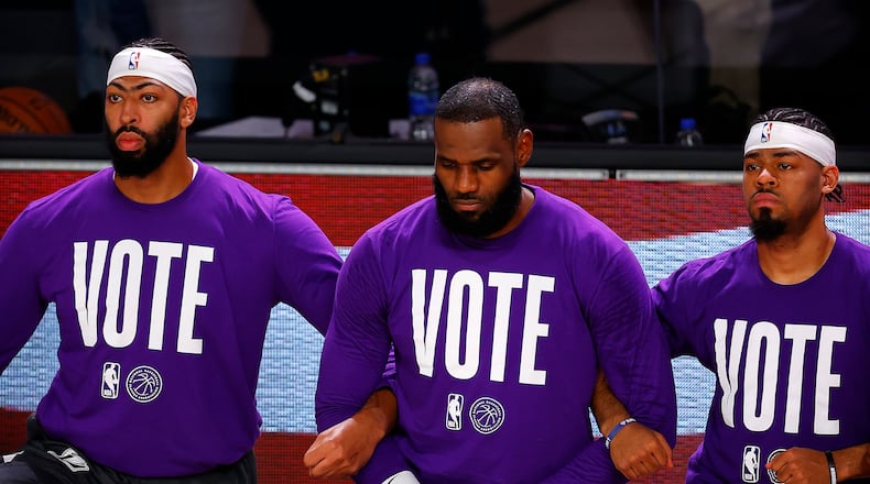 Los Angeles Lakers Anthony Davis, left, LeBron James, center, and Quinn Cook kneel during the national anthem with VOTE shirts on prior to the start of the game in September. James has started a voting rights organization that will try to call attention during the All-Star Game weekend in Atlanta to legislation moving through the Georgia Legislature that would place restrictions on voting. (Mike Ehrmann/Getty Images/TNS)